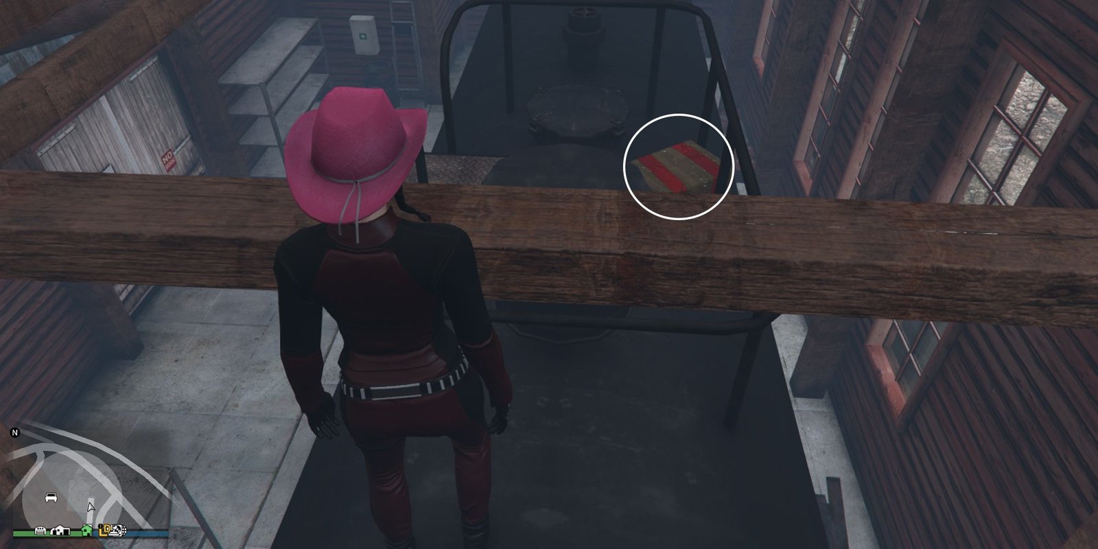 Image depicts a female character in GTA Online at Grapeseed Rail Terminus on top of the rail tanker in the railway shed. There is a ladder on the left-hand side, and a wooden beam in the centre of the image, with G's Cache just behind this beam on the right.