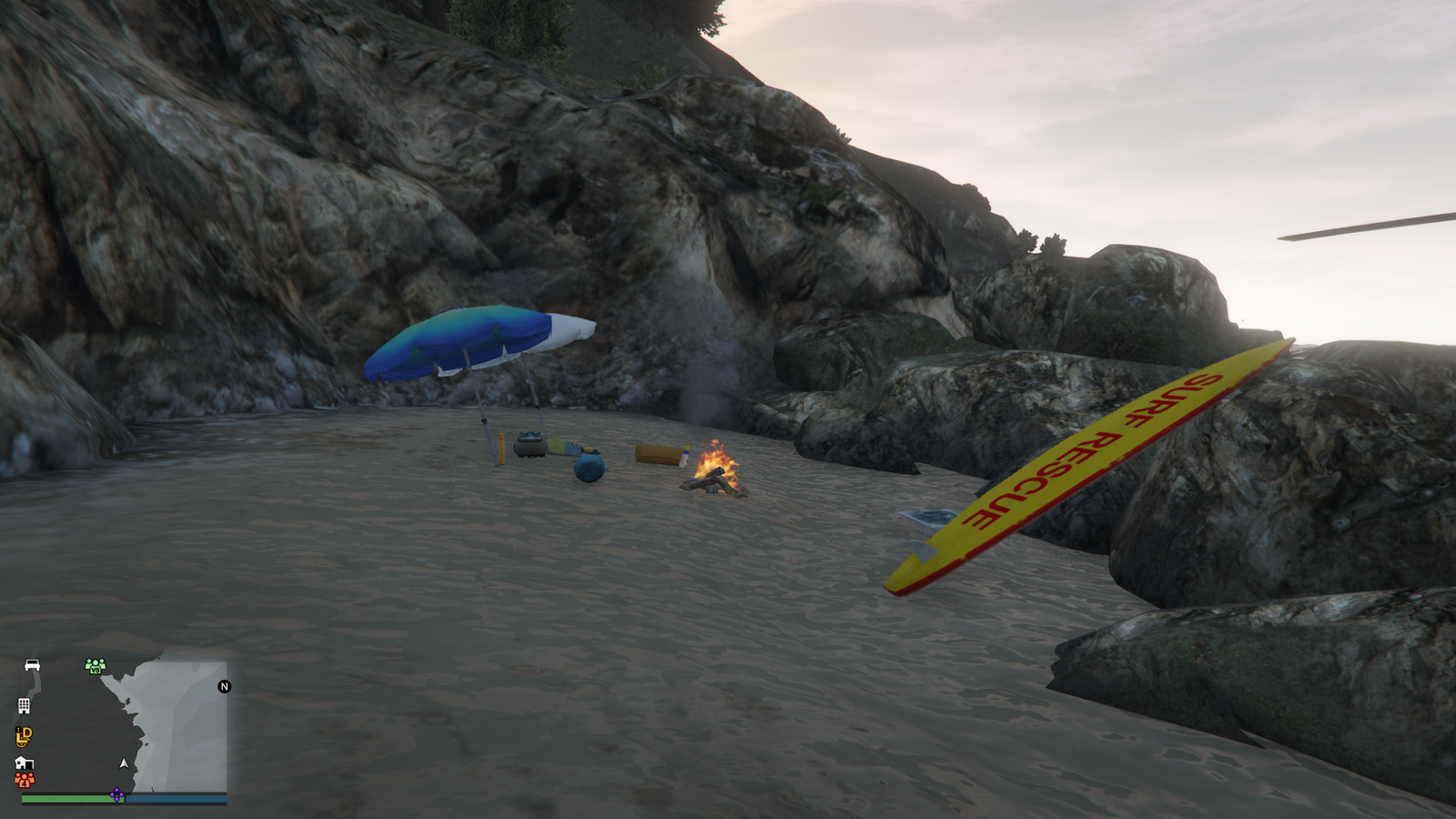 a small cove on a sandy beach with some surf equipment and a small fire in gta 5