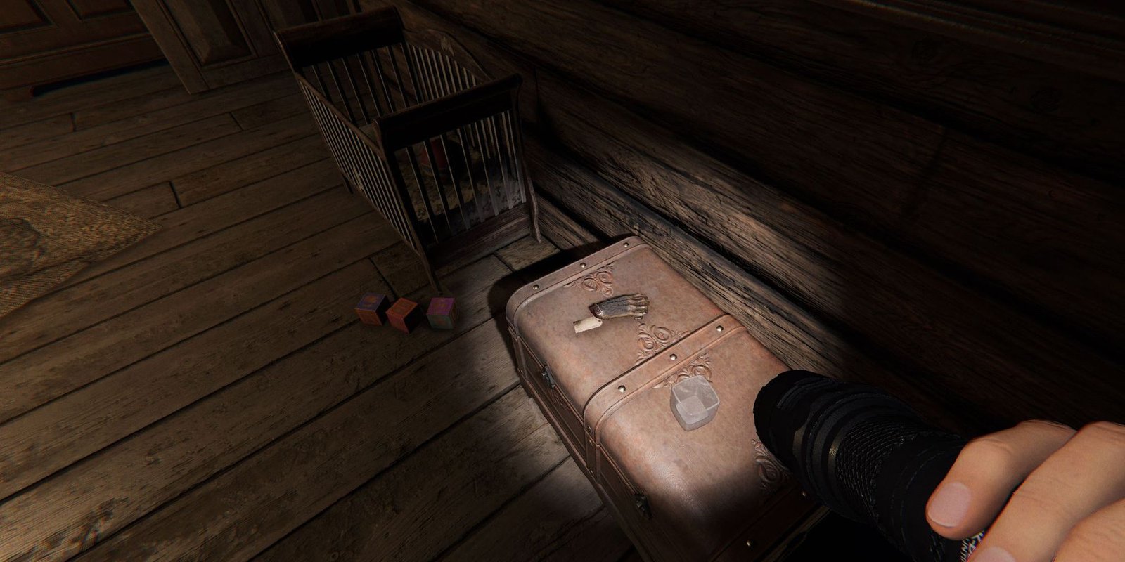 Image depicts a small monkey paw hand on a leather chest in a child's room in Phasmophobia. This image is from Bleasdale Farmhouse.