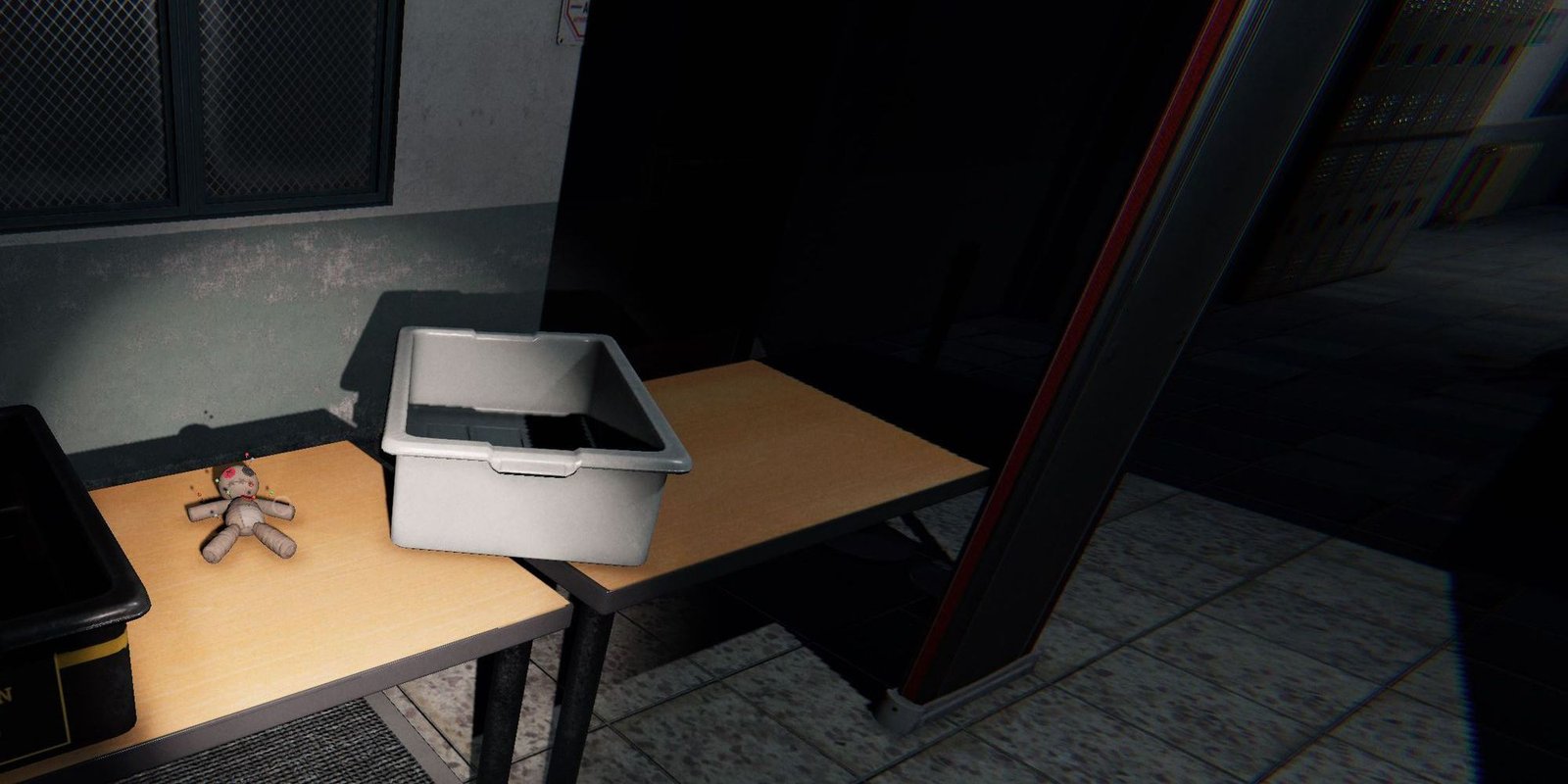 Image depicts a voodoo doll on a desk next to a grey plastic box in the Prison in Phasmophobia.
